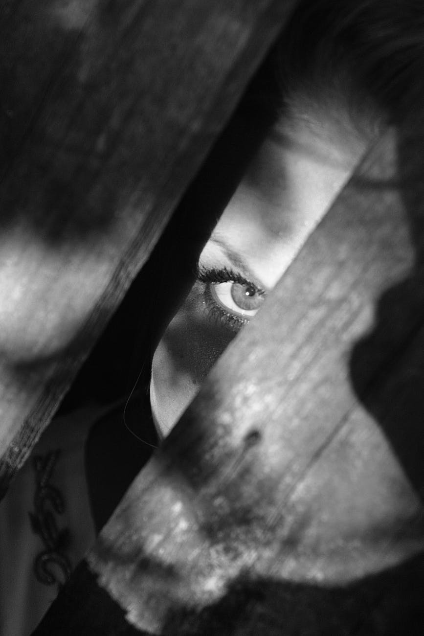 grayscale photo of woman peeking on planks
